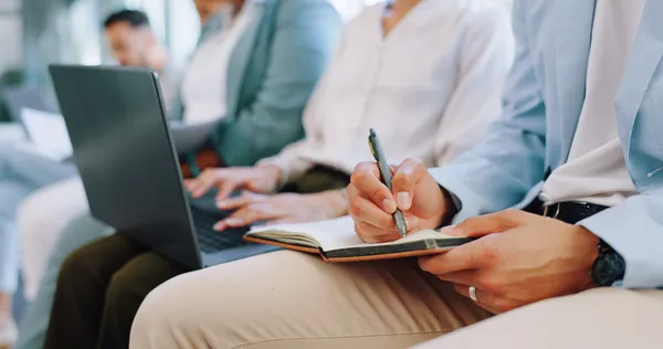 Manos de candidatos escribiendo notas en un cuaderno durante una entrevista de reclutamiento de personal.