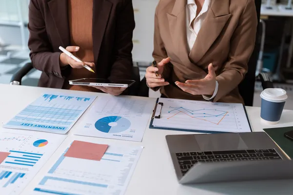 Dos profesionistas revisando gráficos y documentos financieros como parte del proceso de maquila de nómina en la oficina.